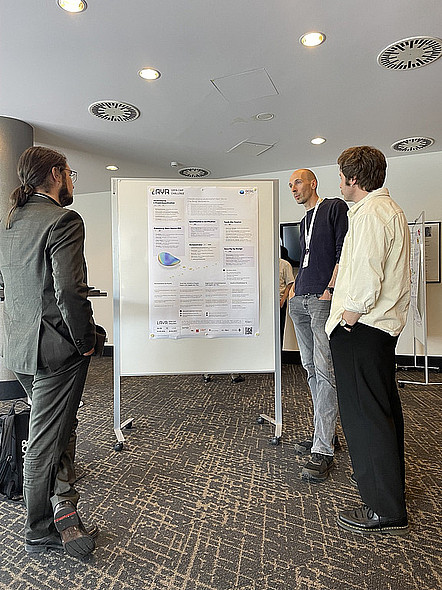 Drei Personen stehen vor einem wissenschaftlichen Plakat und unterhalten sich