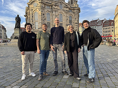 Fünf Personen stehen auf einem Platz vor der Frauenkirche ein Dresden